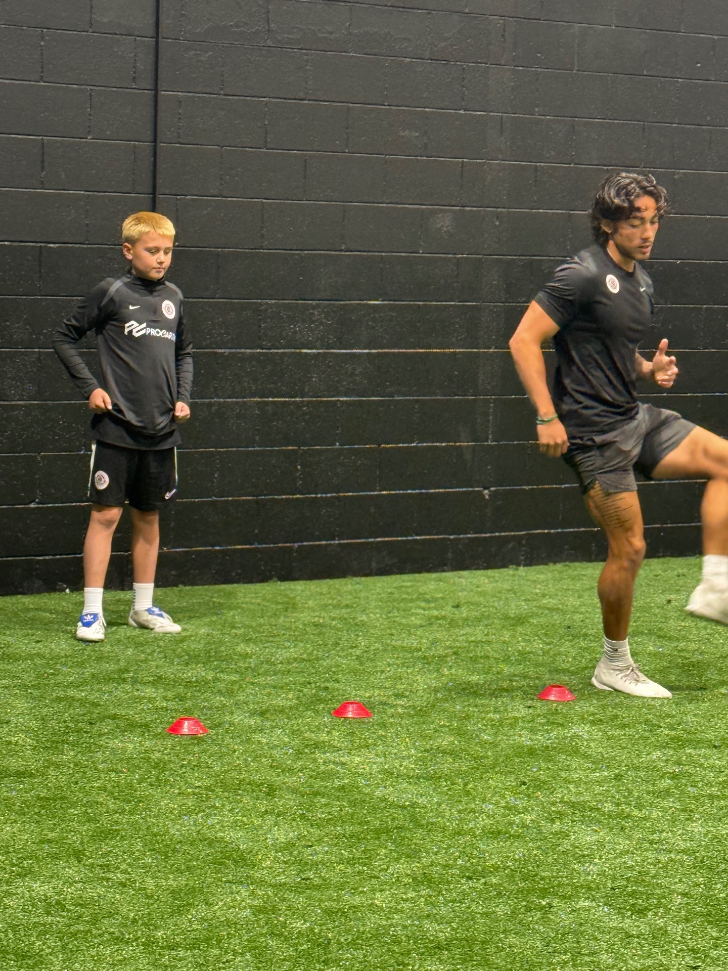 Players working through a cone footwork drill on the indoor field